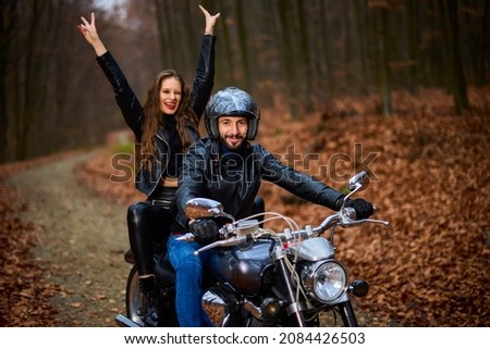 Couple of motorcyclists with a chopper in the woods in the fall.