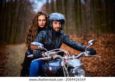 Couple of motorcyclists with a chopper in the woods in the fall.
