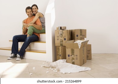 Couple moving house, taking tea break at bottom of staircase near stack of boxes, smiling, portrait - Powered by Shutterstock