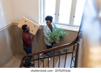 Couple Moving Into New Home Carrying Box Upstairs. Couple moving into new apartment. Happy young couple moving carboard boxes and furnitures during move into a new home flat apartment - Shutterstock ID 2070295166