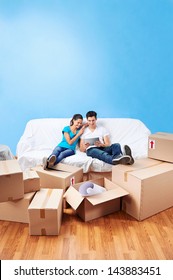 couple moving in together relaxing on sofa couch with laptop tablet computer and boxes