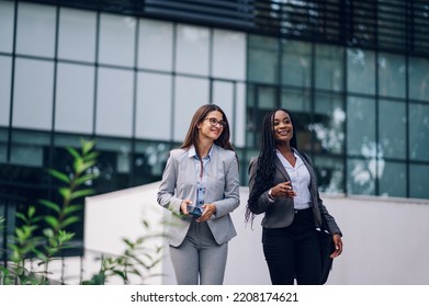 Couple Of Multiracial Business Woman In Motion Talking About Their Project While Outside Of The Office Building. Young Diverse Confident Corporate People. Copy Space.