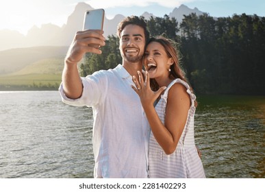 Couple, nature selfie and engagement by lake for celebration, happiness and excited for future. Man, woman and photography for social media, profile picture and romance with love, proposal and goals - Powered by Shutterstock