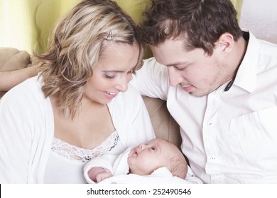 Couple With New Baby At Home On The Sofa