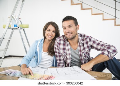 Couple In New Home Choosing Wall Paint Colors