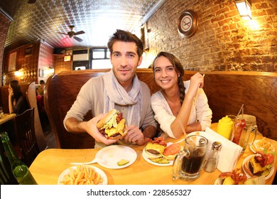 Couple In New York City Eating Hamburger In Restaurant