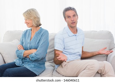 Couple Not Taking After A Fight And Man Looking Confused At Camera At Home On Couch