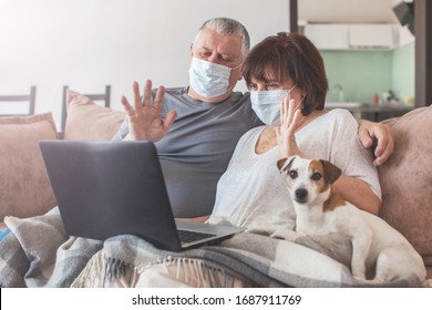 Couple Old Aged Senior People At Home With Seasonal Winter Cold Illness Talking Skype Sit Down On The Sofa. Elderly Couple In Medical Masks During The Pandemic Coronavirus CoVid-19