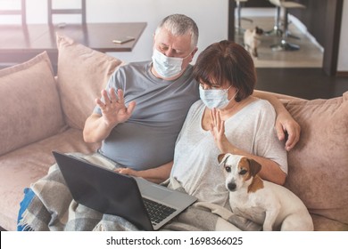 Couple old aged senior people at home with seasonal winter cold illness talking skype sit down on the sofa. Elderly couple in medical masks during the pandemic Coronavirus CoVid-19