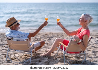 Couple old mature people on the sand at the beach sitting enjoying drink juice and living the moment - Powered by Shutterstock