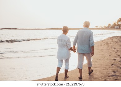 Couple of old mature people walking on the sand together and having fun on the sand of the beach enjoying and living the moment. Two cute seniors in love having fun. - Powered by Shutterstock