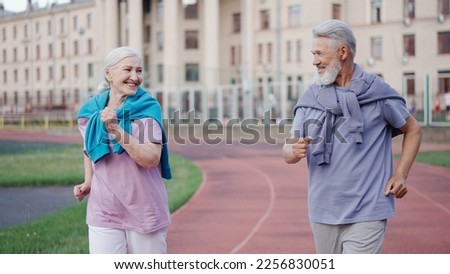 Couple old men run marathon stadium arena. Romantic elderly people sport training. Elder grandparents couple jog together. Granny and Grandpa workout. Love old athletes. Active lifestyle senior person