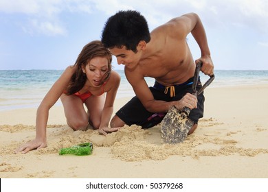 Couple On The Beach In Hawaii Digging For Buried Treasure