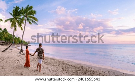 couple on the beach with palm trees watching the sunset at the tropical beach of Saint Lucia or St Lucia Caribbean Island. men and women on vacation in St Lucia a tropical island with palm trees