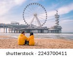couple on the beach of Scheveningen Netherlands during Spring, The Ferris Wheel at The Pier at Scheveningen in the Netherlands, Sunny spring day at the beach of Holland
