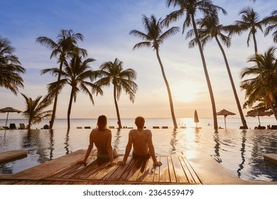 couple on the beach at sunset, honeymoon travel, man and woman sitting near swimming pool in hotel resort