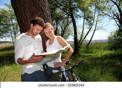 Couple on a bike ride making a stop to look at map - Powered by Shutterstock