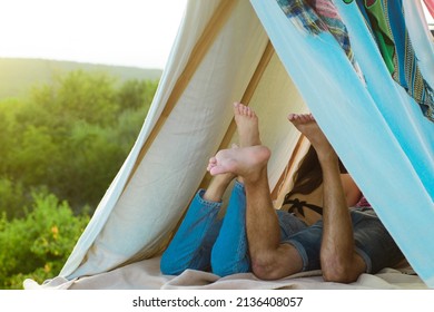 Couple on camping in tent. Focus on feet. Couple in love. Girlfriend and boyfriend on romantic weekend in nature. Back legs view of couple in love. Lovers in tent outdoor.