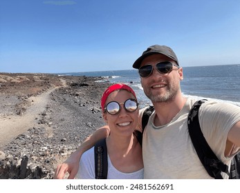 Couple on cliff overlooking beach with rocky shoreline in background - Powered by Shutterstock