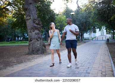 Couple on date in park, ice cream and holding hands outdoor, love and commitment in relationship. Romance in nature, black man and woman eat dessert for quality time together, trust and interracial - Powered by Shutterstock