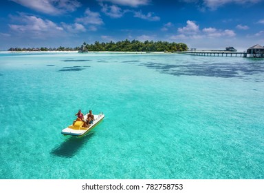 Couple On A Floating Pedalo Boat Is Having Fun On A Tropical Paradise Location Over Turquoise Waters And Blue Sky