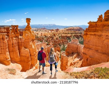 Couple On Hiking Trip Looking At Beautiful  Mountain Landscape,  People Relaxing On Top Of The Mountain. Famous Thor's Hammer Hoodoo. Bryce Canyon National Park, Utah, USA