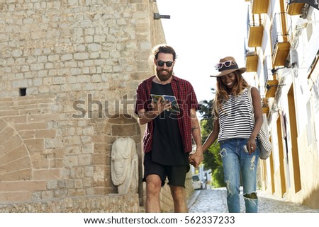 Couple on holiday walk, reading a guidebook, three quarters