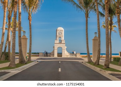 A couple on the left of the clock tower stands to view the waves of the ocean while the couple on the right sits on the stone rail ledge deep in conversation. Beautiful sculpted detail adorns tower.  - Powered by Shutterstock