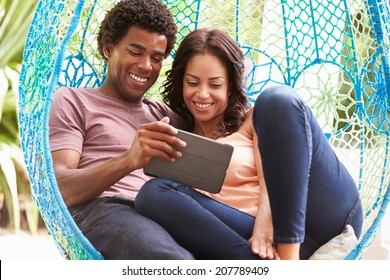 Couple On Outdoor Garden Swing Seat Using Digital Tablet - Powered by Shutterstock