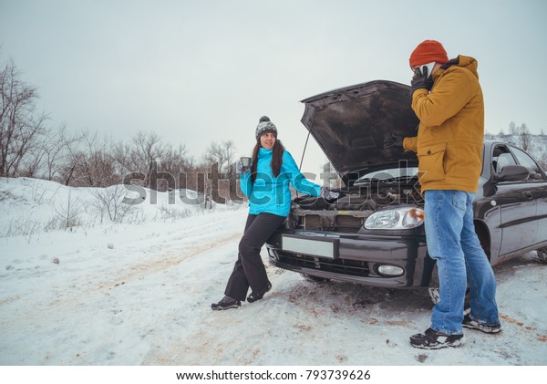 couple on the\
road with broken in cold winter\
day