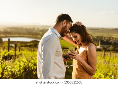 Couple on a romantic date standing together drinking red wine in a wine farm. Couple on a wine date spending time together. - Powered by Shutterstock