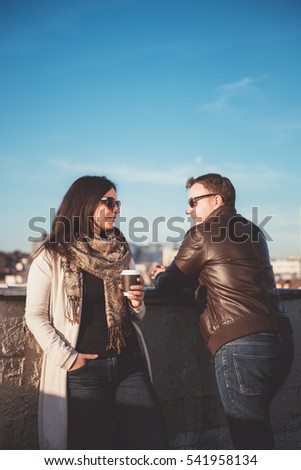 Couple on the rooftop talking and drinking coffee