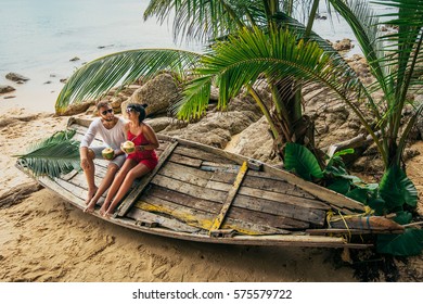Couple on the shore of Paradise island. Couple in love on the seaside drinking coconut. Man and woman drink coconut. Honeymoon trip. Lovers on the beach. Wedding travel. Holiday romance. Sea tour