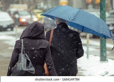 couple on snowy street with umbrella