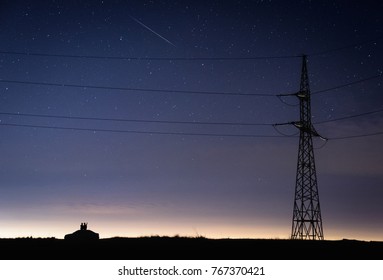 Couple On Top Of A Car Watching Stars And Comets Under Electrical Pillar