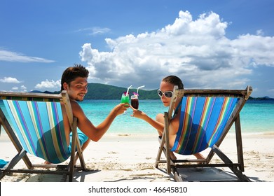 Couple On A Tropical Beach In Chaise Lounge