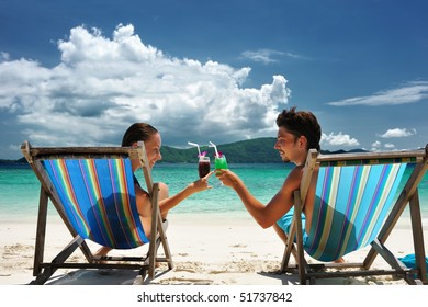 Couple On A Tropical Beach In Chaise Lounge