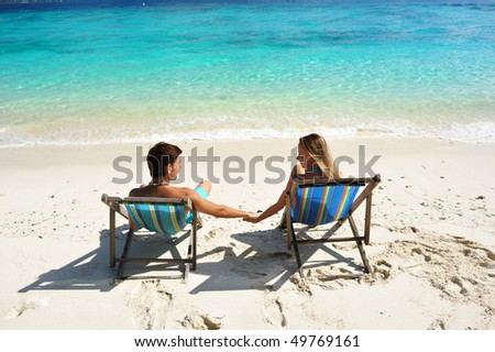 Couple on a tropical beach in chaise lounge