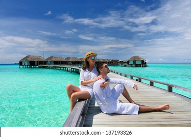 Couple On A Tropical Beach Jetty At Maldives