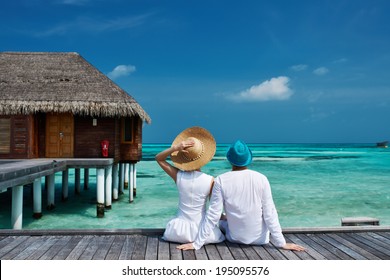 Couple On A Tropical Beach Jetty At Maldives