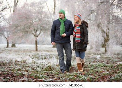 Couple On Winter Walk Through Frosty Landscape