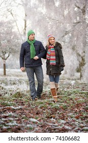 Couple On Winter Walk Through Frosty Landscape