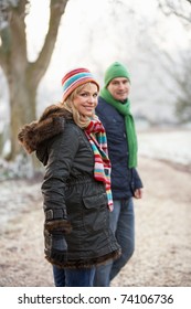 Couple On Winter Walk Through Frosty Landscape