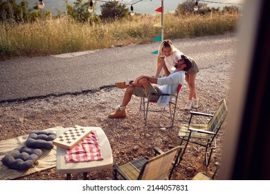 Couple Outdoors Laughing In Front Of Camper Rv. Roadtrip Summer Holiday. Fun, Togetherness, Travel, Nature Concept.