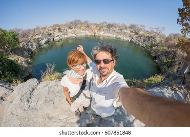 Couple With Outstretched Arms Taking Selfie At Otjikoto Lake, One Of The Only Two Permanent Natural Lake In Namibia, Africa. Concept Of Adventure And Traveling People. Fish Eye View.
