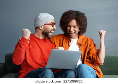 Couple of overjoyed friends using laptop computer, watching football game, sports betting, win money  sitting on couch at home. Happy student reading test results, celebration success - Powered by Shutterstock