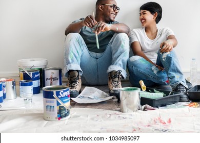 Couple painting house wall