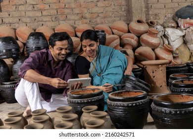Couple painting pots while old father is shaping the clay into pot on spinning wheel
