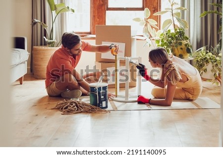 Couple painting wooden table by recycle, donate and thrift furniture for a new home improvement project in new apartment. Creative and DIY man and woman with reusable objects, decorating their house