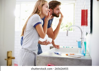 Couple In Pajamas Putting On Moisturizer In Bathroom - Powered by Shutterstock